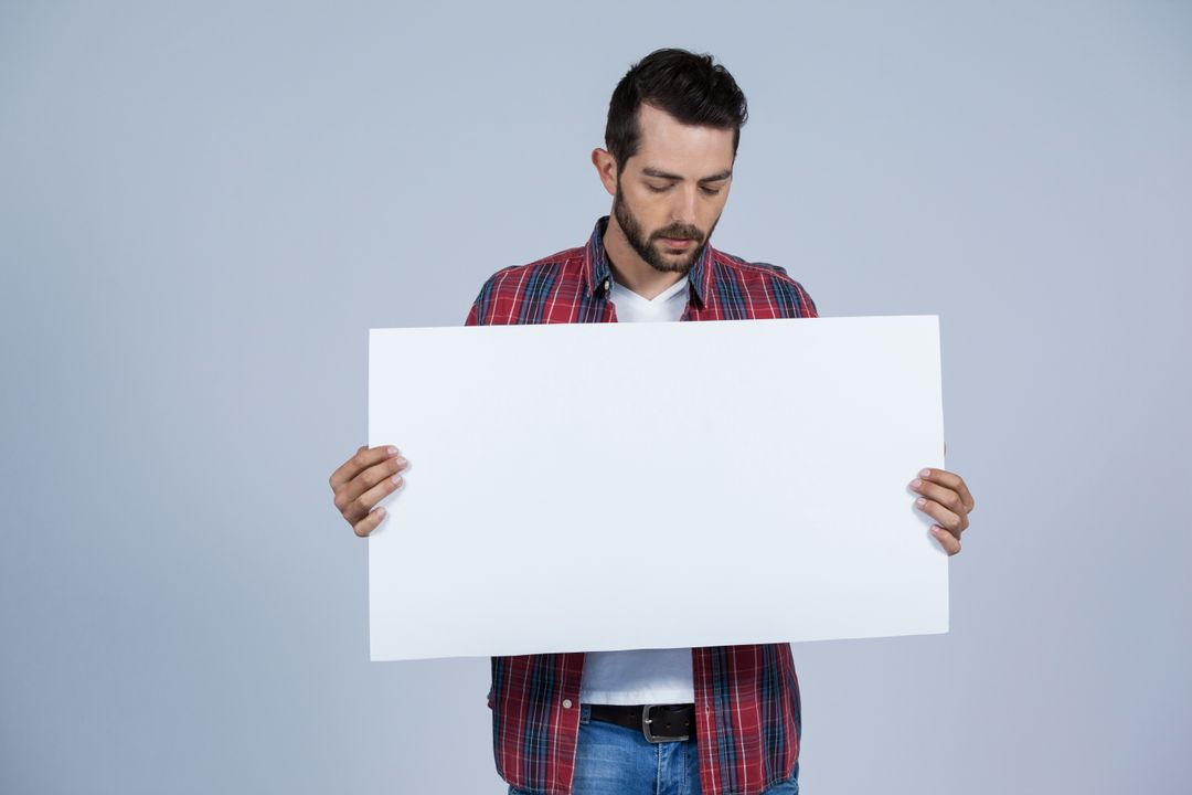 Man wearing casual clothes holding a large blank white card