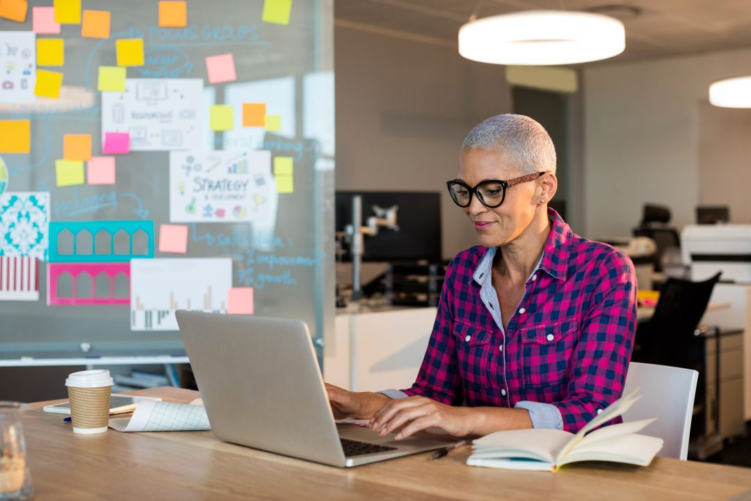 Image of a woman working on her laptop and sticky notes in the background on a board - Topics and ideas for blogs that will inspire you and keep your readers engaged - Image
