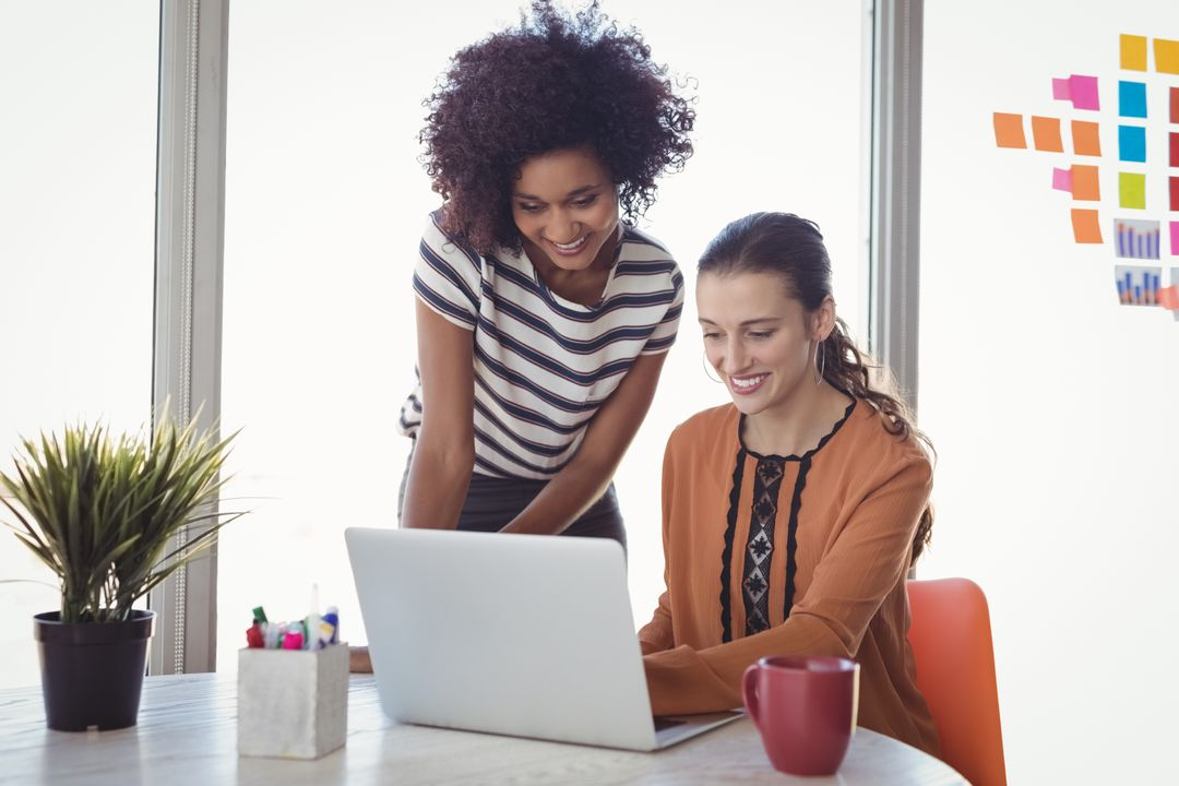 Image of a woman sitting and a woman standing working on the same laptop - Topics and ideas for blogs that will inspire you and keep your readers engaged - Image