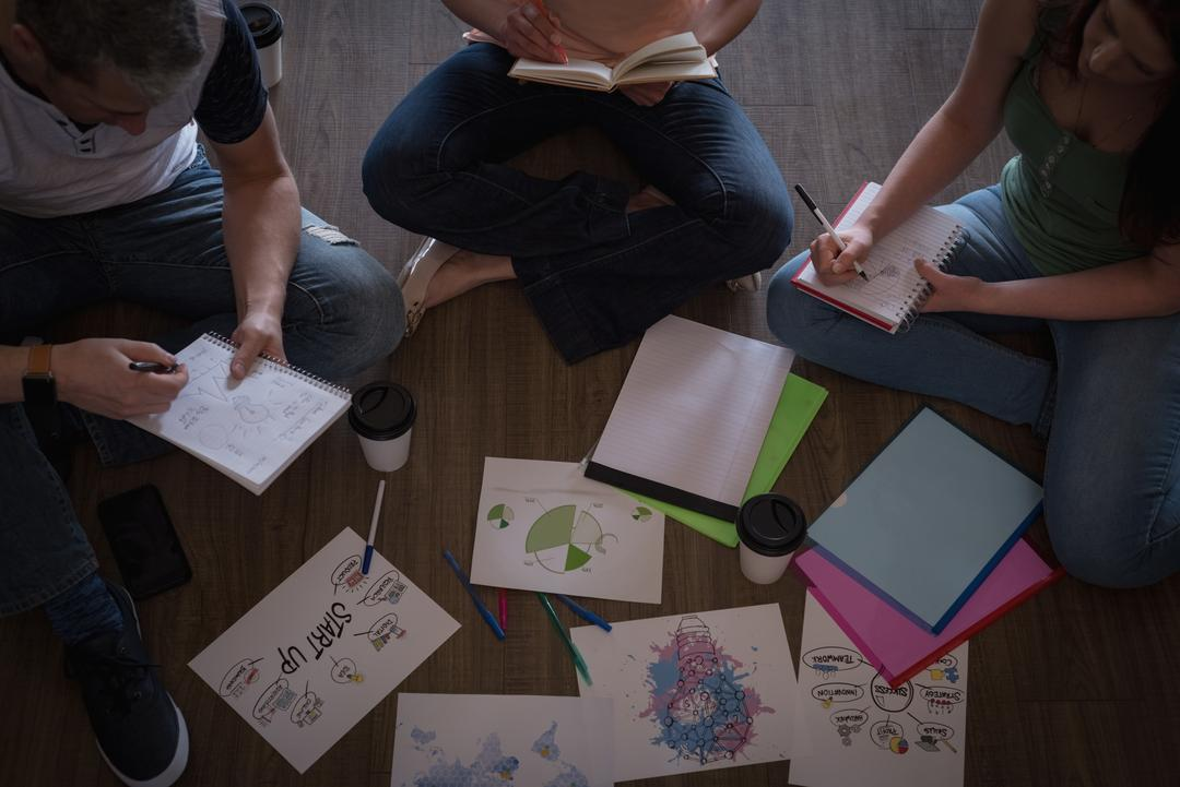 Image of three people sitting on the ground and taking notes on their notebooks  - The beginner's guide to YouTube marketing, how to increase subscribers quickly - Image