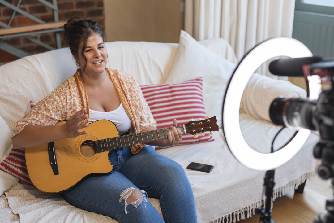 Image of a woman sitting on a couch in front of a camera and playing guitar - The beginner's guide to YouTube marketing, how to increase subscribers quickly - Image
