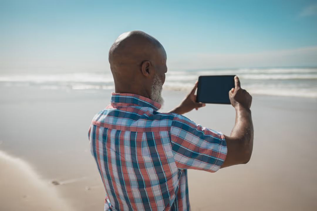 Man standing on a beach taking photographs - A complete guide to standard photo sizes to find the perfect resolution & aspect ratio for your design - Image