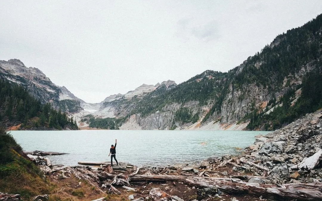 Image of a person standing at a lake in the mountains and raising his arm - How to design a good business website: 18 key principles - Image