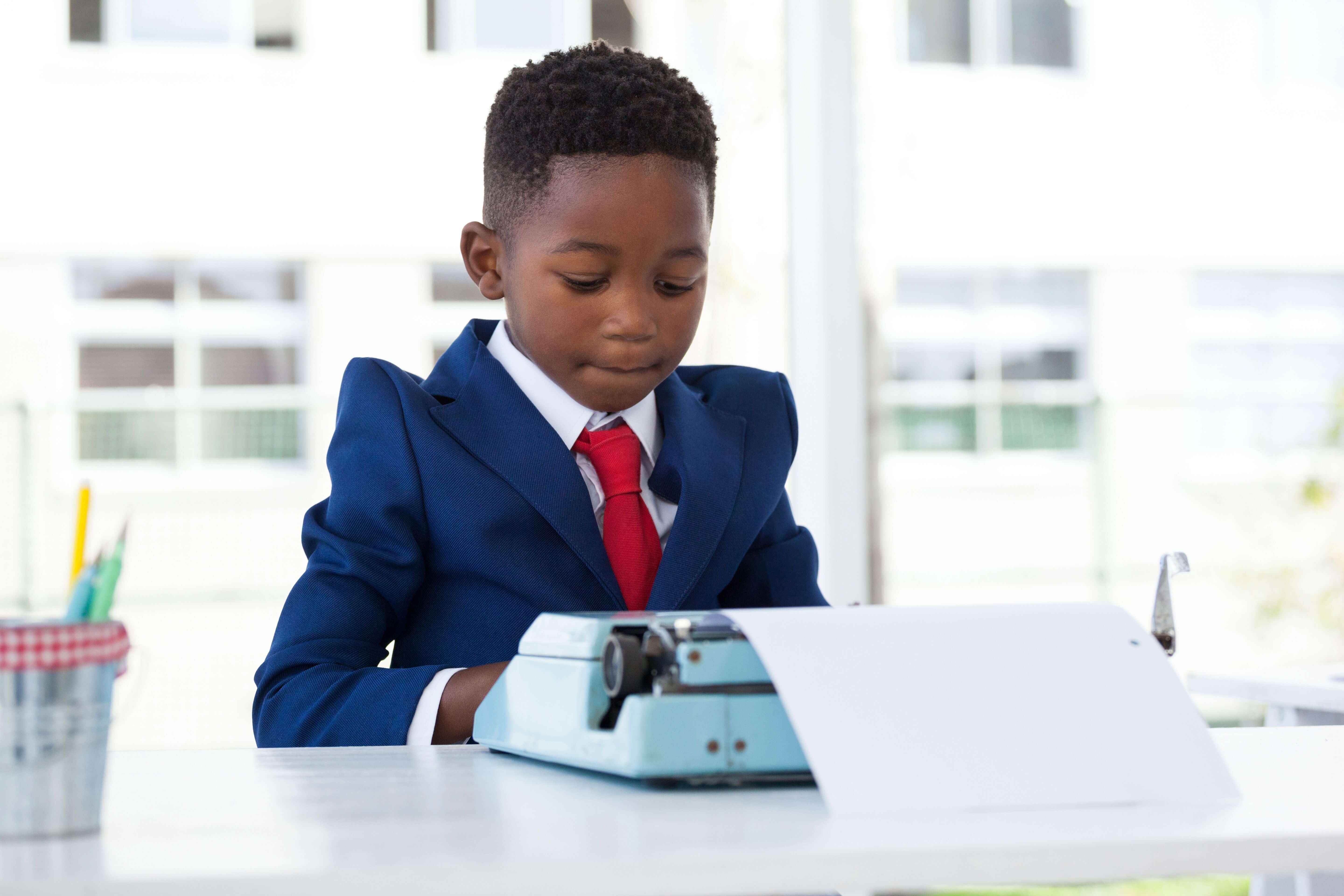 child wearing a suit using a typewriter