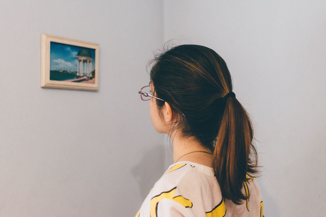 Woman looking at small painting hanging on a wall