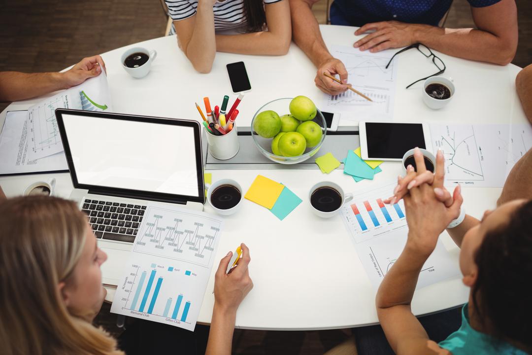 Image of people sitting at a table discussing graphics - Why the ability to make swift decisions is so important for social media content creators - Image