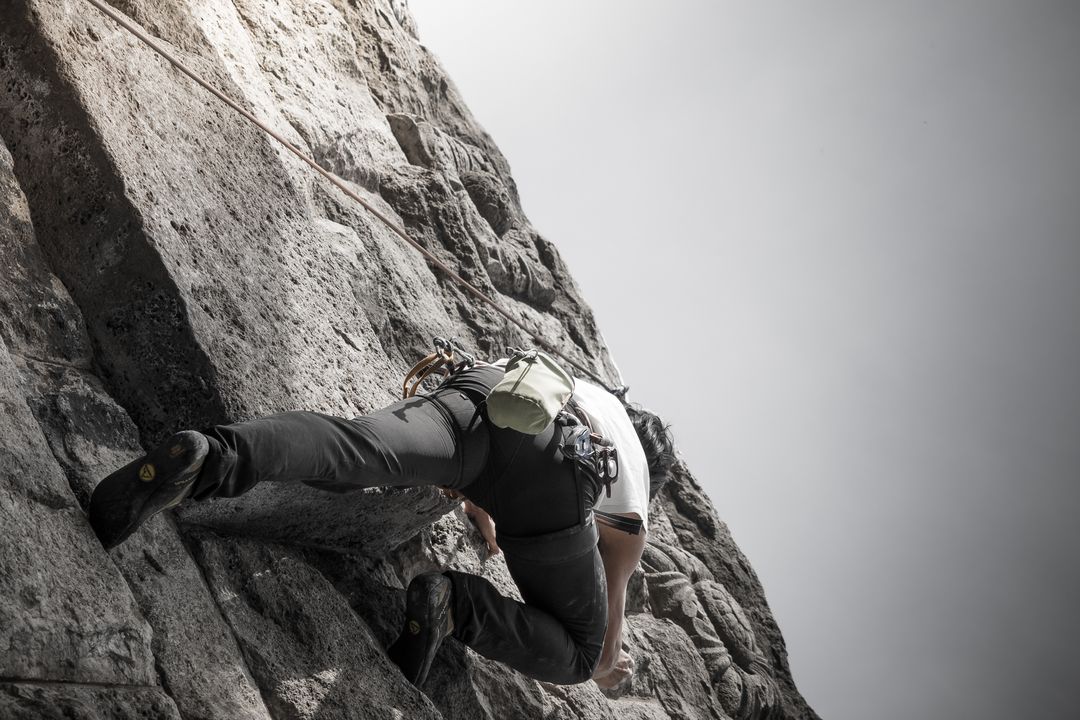 Image of a fitness man rock climbing up a mountain side