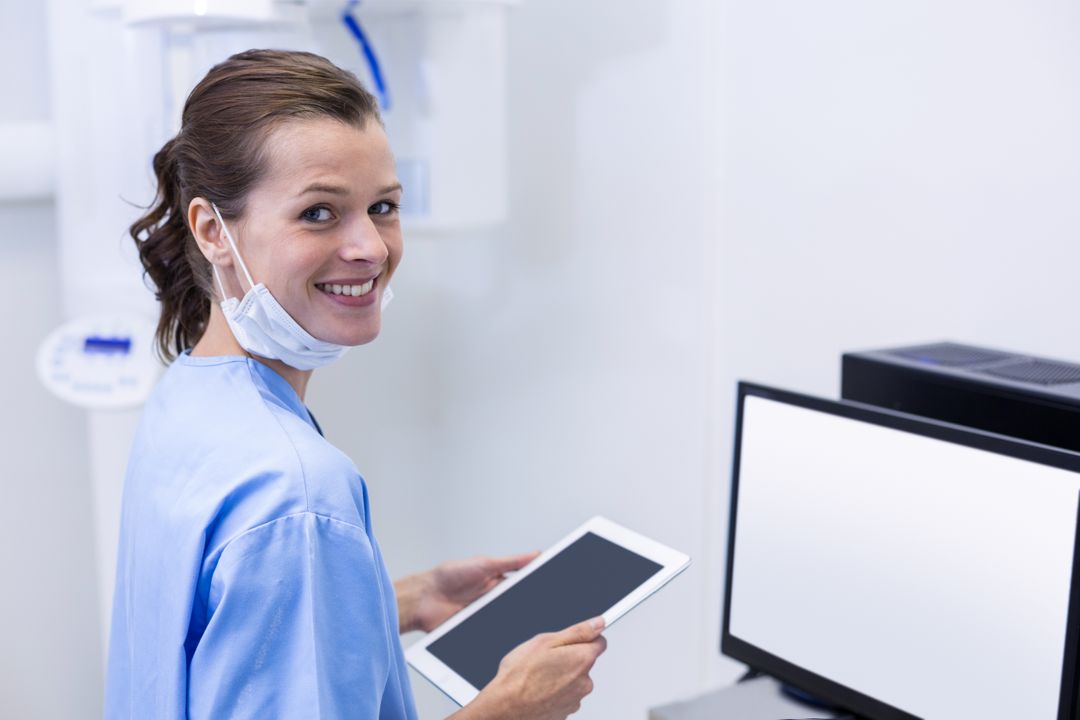 Smiling dental assistant holding digital tablet - Free Images, Stock Photos and Pictures on Pikwizard.com