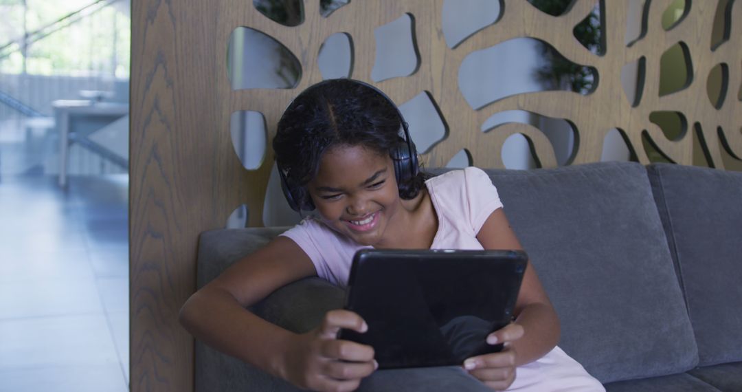 African american girl smiling while using digital tablet sitting on the couch at hospital - Free Images, Stock Photos and Pictures on Pikwizard.com