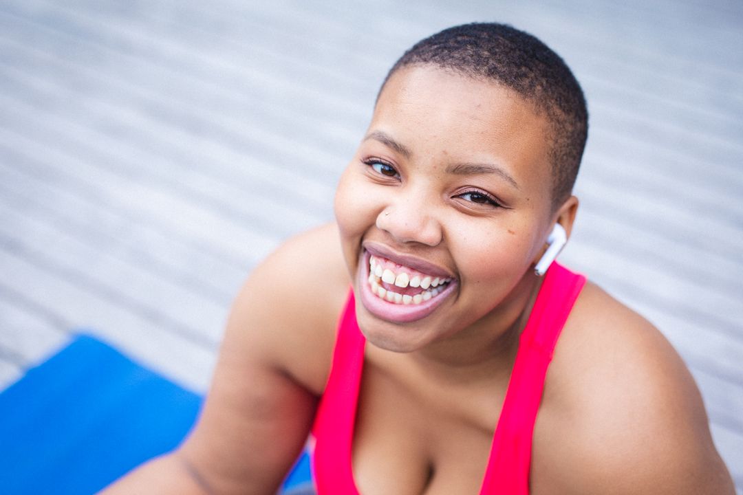 Portrait of african american woman smiling while sitting on yoga mat - Free Images, Stock Photos and Pictures on Pikwizard.com