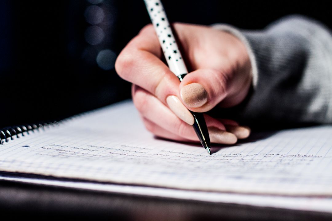 Woman writing on a notepad with a black pen