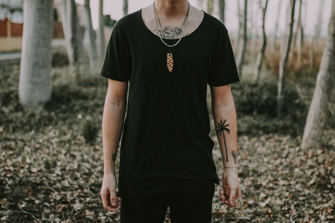 Man standing in forest with tattoos 