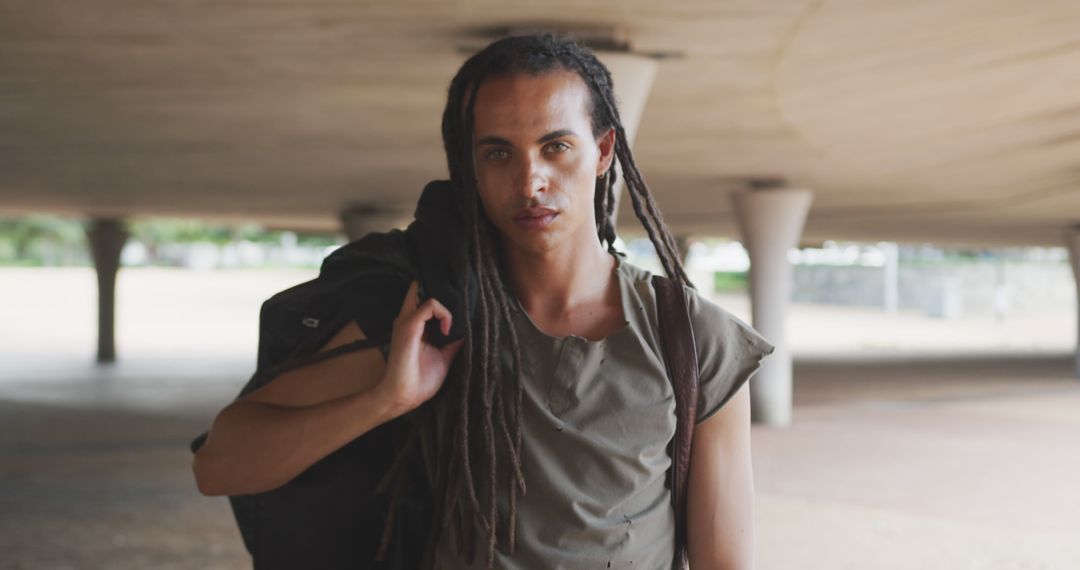 Portrait of fashionable biracial man with dreadlocks wearing backpack and looking at camera - Free Images, Stock Photos and Pictures on Pikwizard.com
