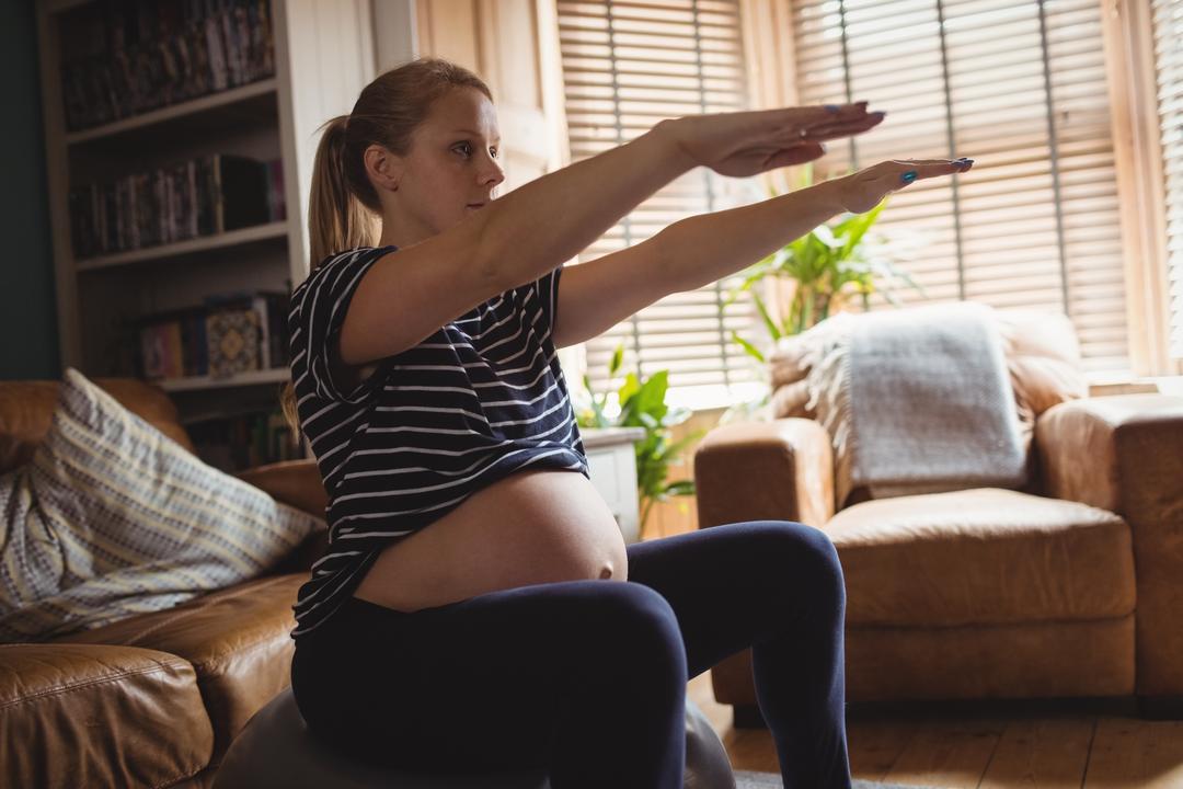Pregnant woman working out in her living room on exercise ball