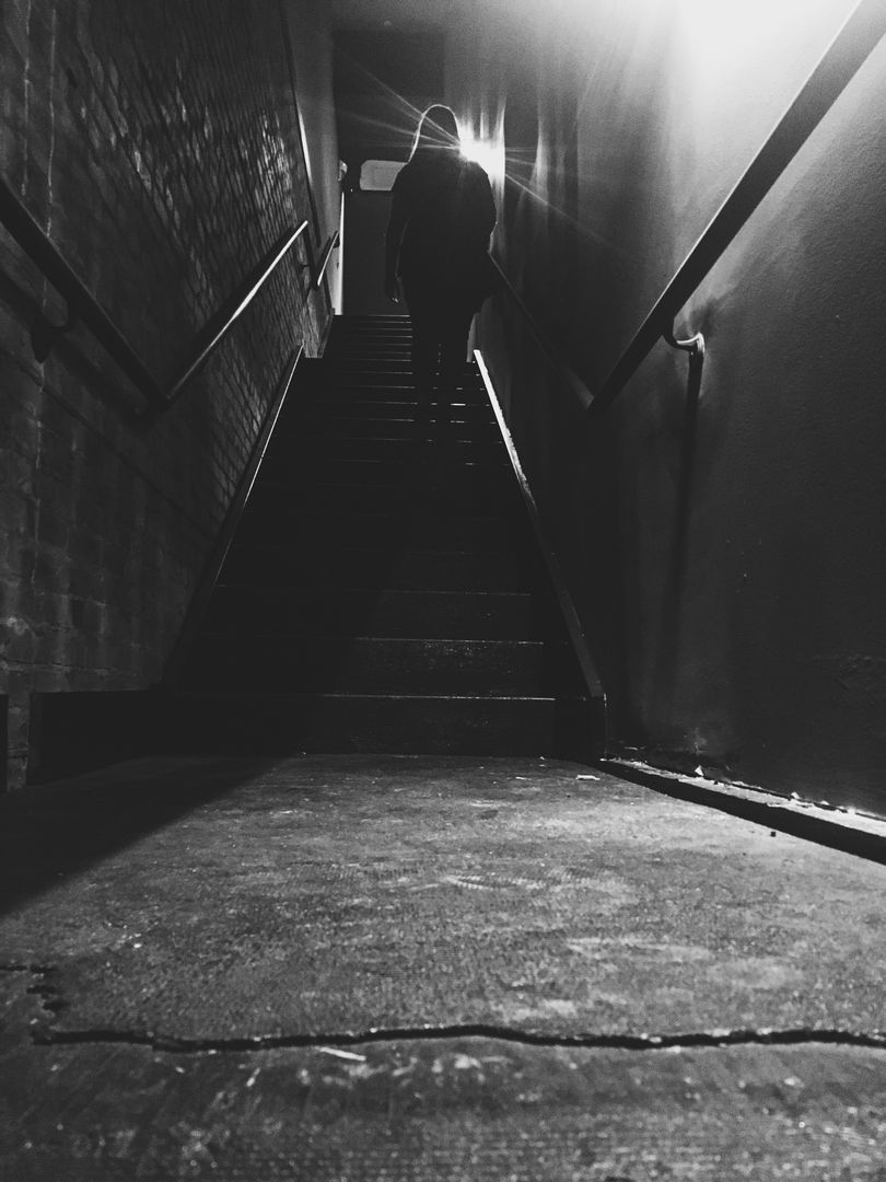 a person walking down a dark stairway - Free Images, Stock Photos and Pictures on Pikwizard.com