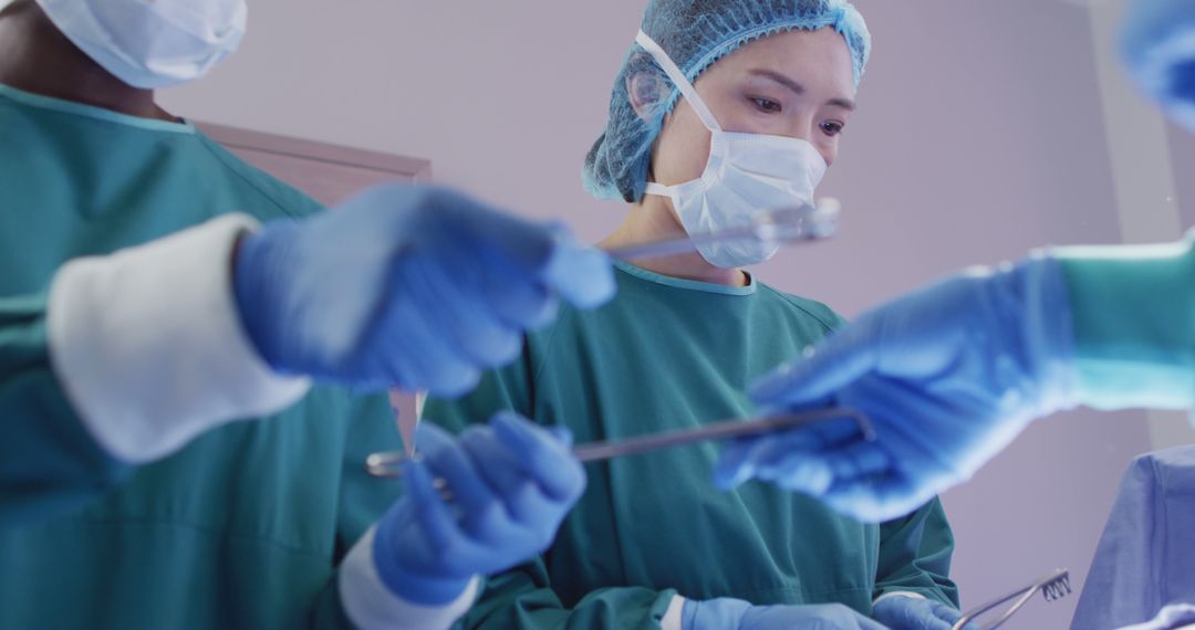 Image of asian female surgeon at work during operation in theatre and colleagues passing instruments - Free Images, Stock Photos and Pictures on Pikwizard.com