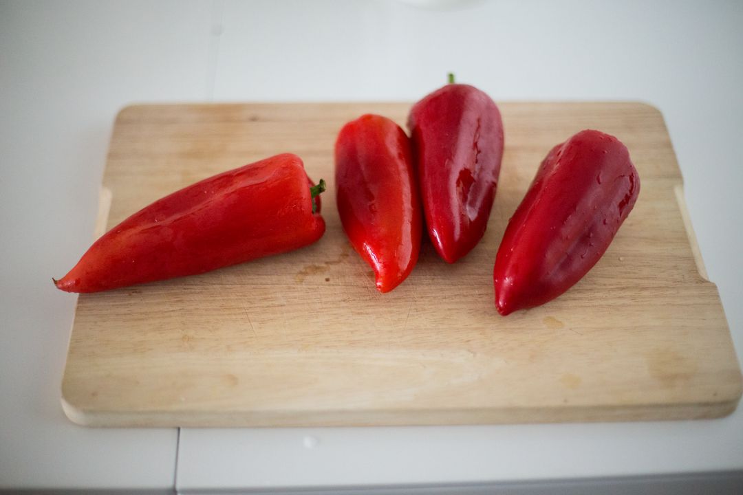 four red peppers on a cutting board - Free Images, Stock Photos and Pictures on Pikwizard.com