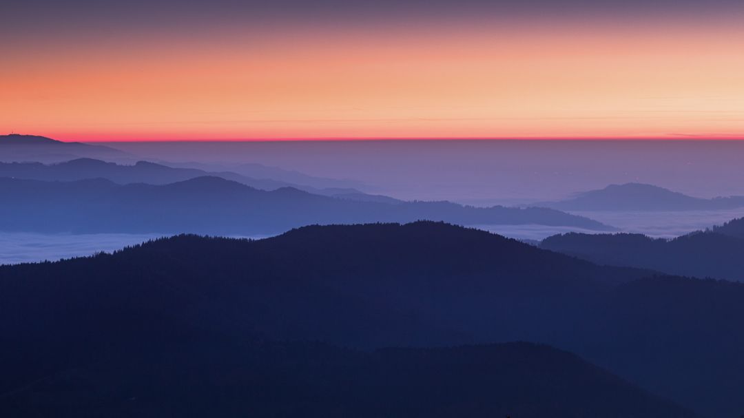 Image of a blue, purple and pink sunset behind a mountain landscape