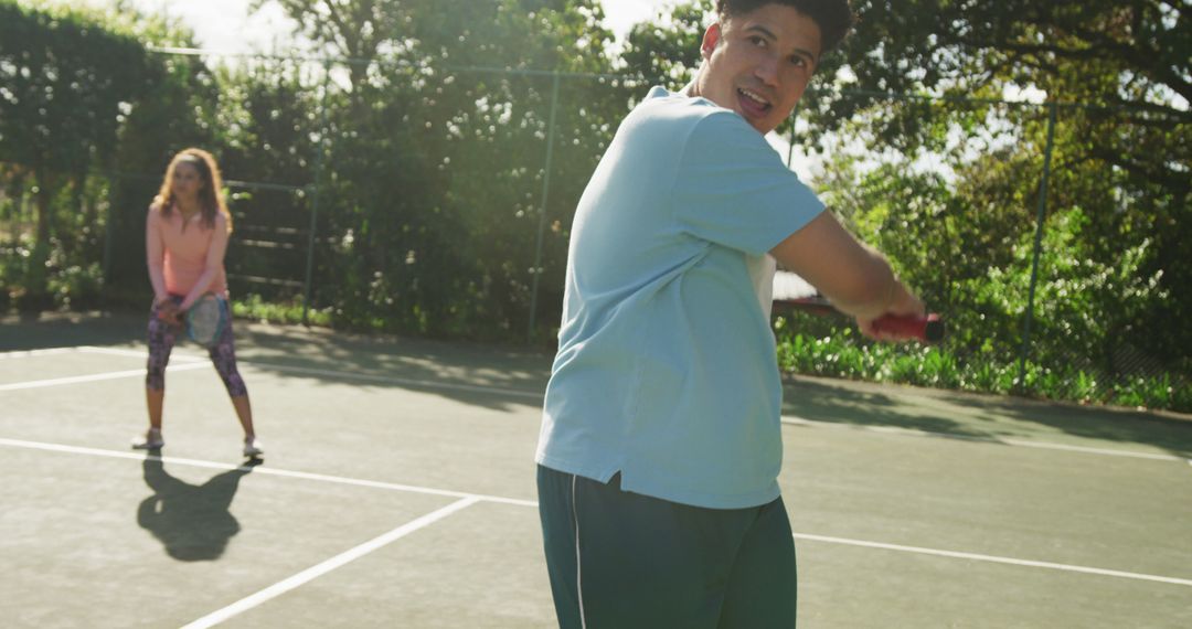 Image of happy biracial couple playing tennis on the court - Free Images, Stock Photos and Pictures on Pikwizard.com