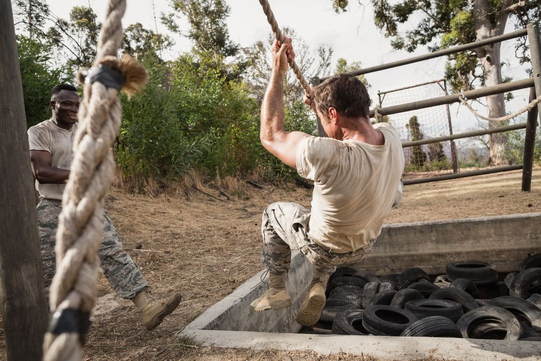 Young military soldiers practicing rope climbing during obstacle