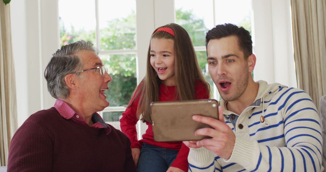 Image of happy caucasian father, grandfather and granddaughter sitting on couch looking at tablet - Free Images, Stock Photos and Pictures on Pikwizard.com