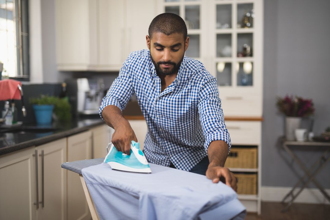 Young man ironing cloth in domestic kitchen from Pikwizard
