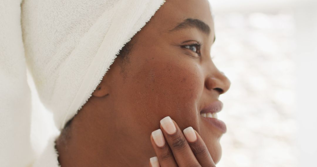 Image of happy african american woman in robe moisturizing face - Free Images, Stock Photos and Pictures on Pikwizard.com