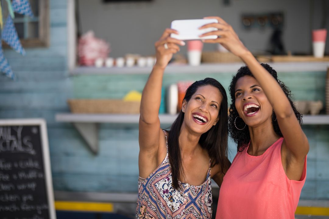 Two friends smiling taking a picture on smartphone