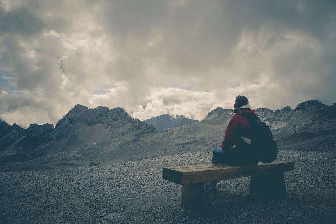a person sitting on a bench in front of a mountain range - Free Images, Stock Photos and Pictures on Pikwizard.com