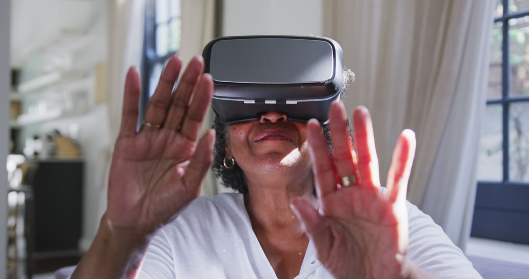 Senior african american woman sitting on sofa and using vr headset - Free Images, Stock Photos and Pictures on Pikwizard.com