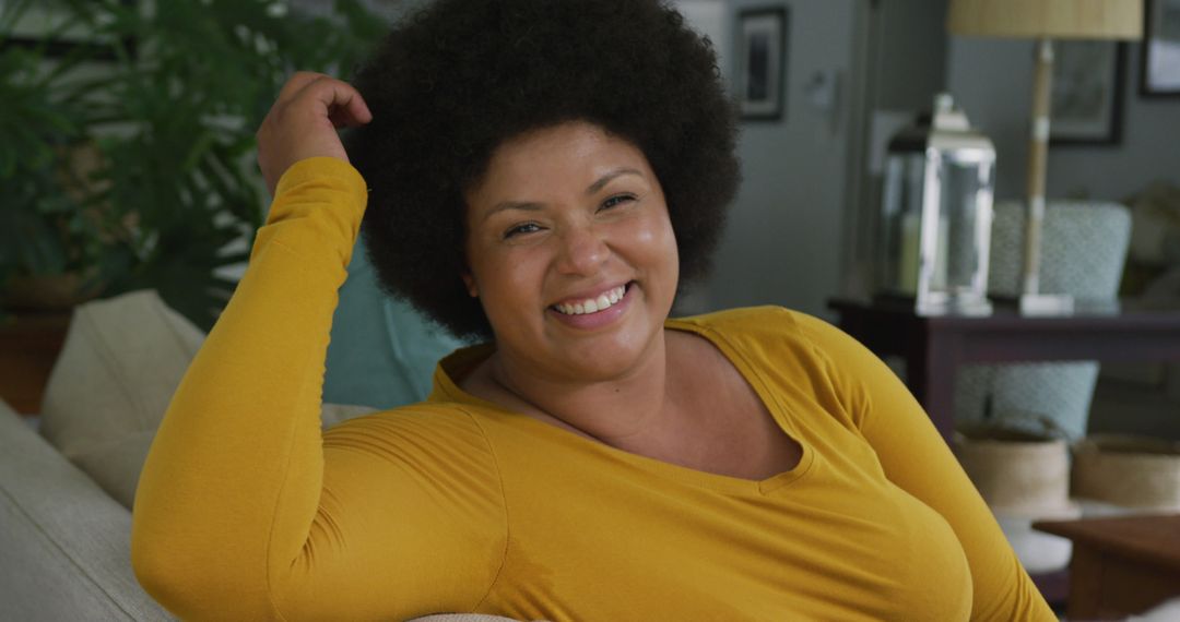 Image of happy plus size african american woman sitting on sofa - Free Images, Stock Photos and Pictures on Pikwizard.com