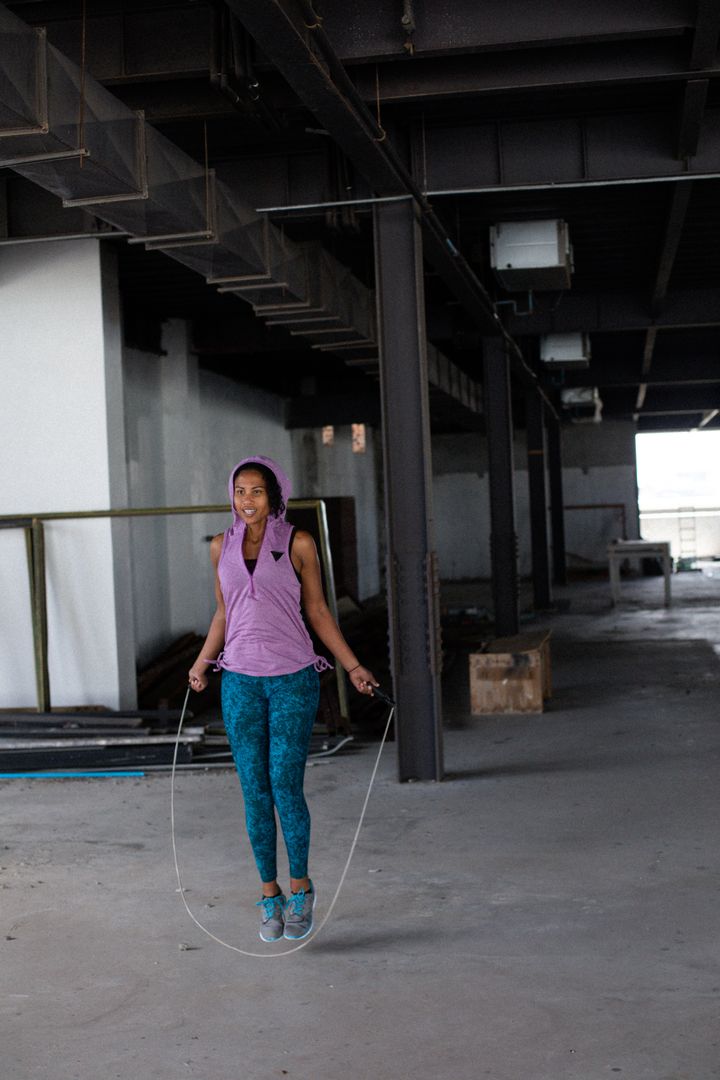 African american woman wearing sports clothes skipping the rope in empty urban building - Free Images, Stock Photos and Pictures on Pikwizard.com