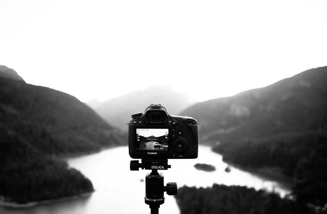 Black and White Image of a Camera on a Tripod with Mountains in the Background