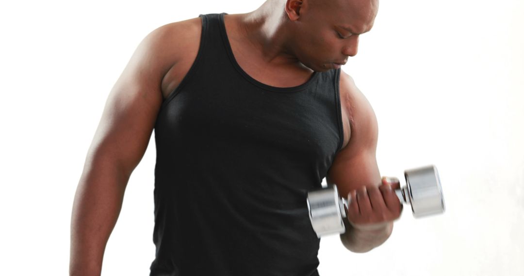 An African American man is focused on lifting a dumbbell, with