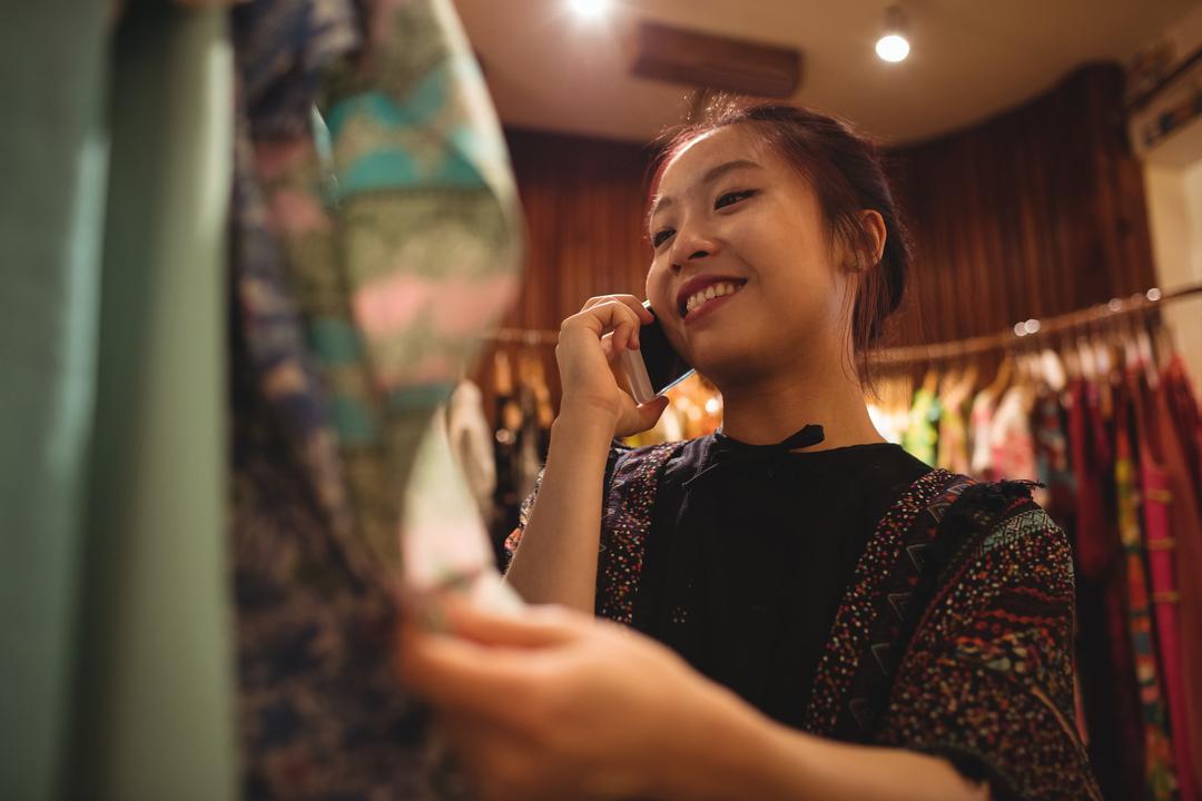 Woman on the phone smiling while looking at clothes