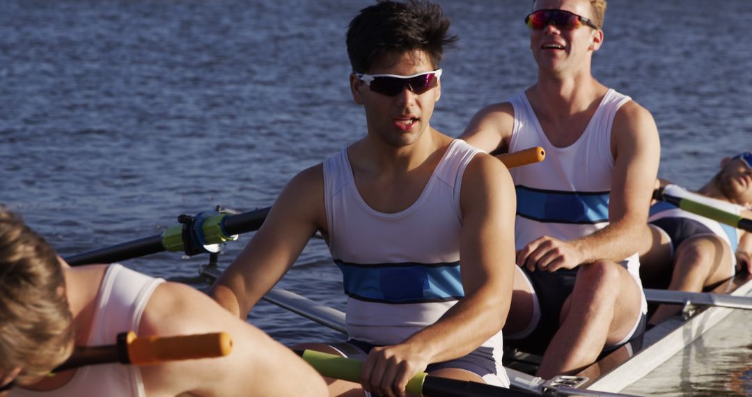 Happy caucasian male rowing team wearing sunglasses in boat on