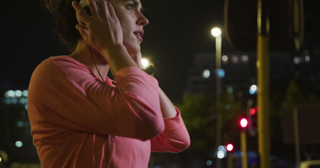 A fit woman with long dark hair in sportswear begins her nighttime city run  with music. from Pikwizard