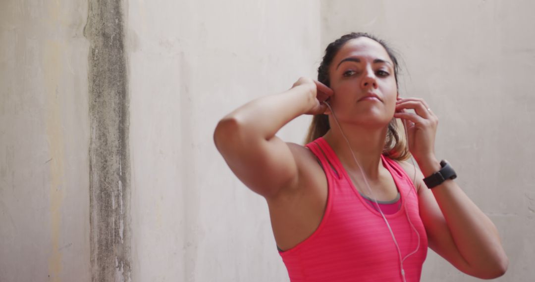 A woman in athletic attire is seen inserting earphones while