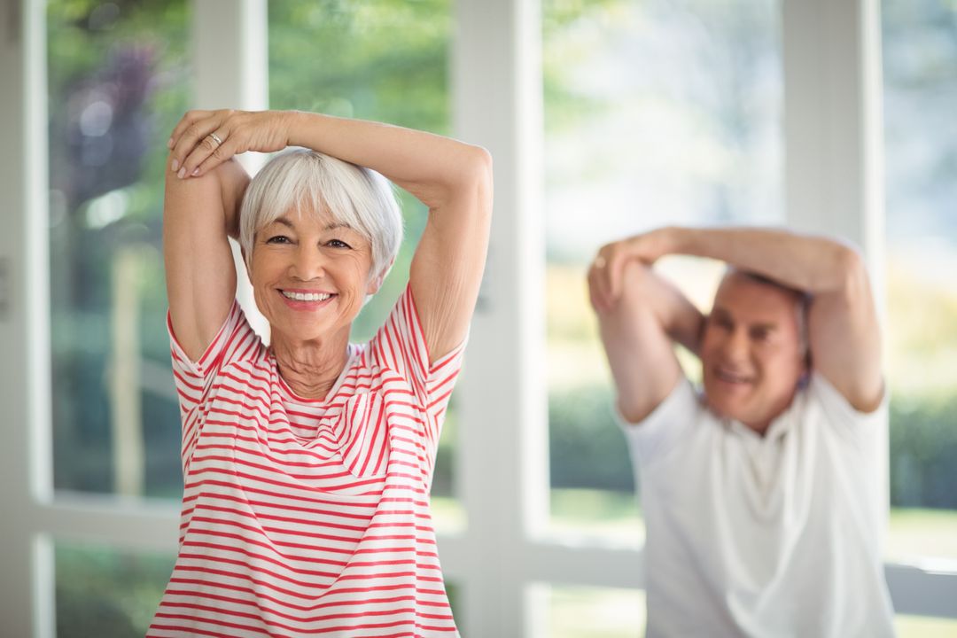 Elderly couple stretching in their living room for fitness blog