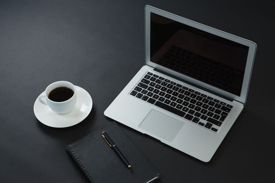 Black coffee, pen, organizer and laptop on black background from Pikwizard