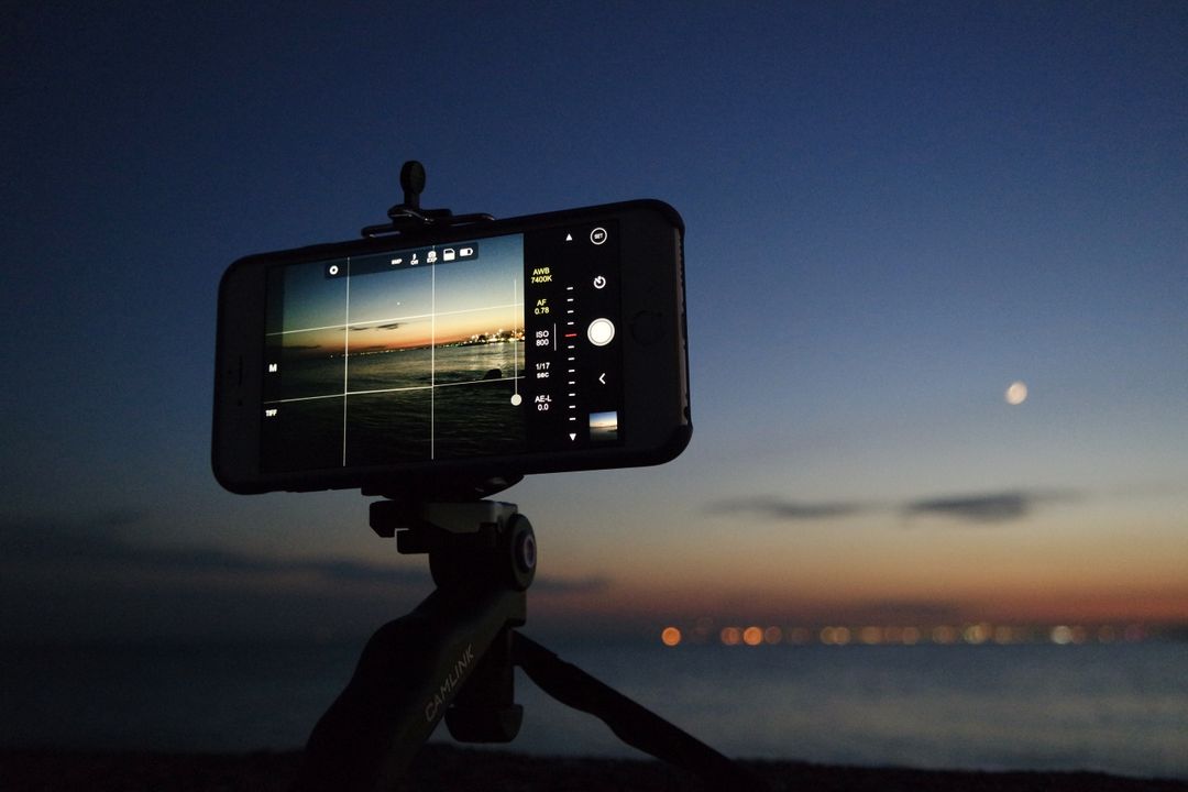 Phone placed on a tripod, taking a picture of the sky and water