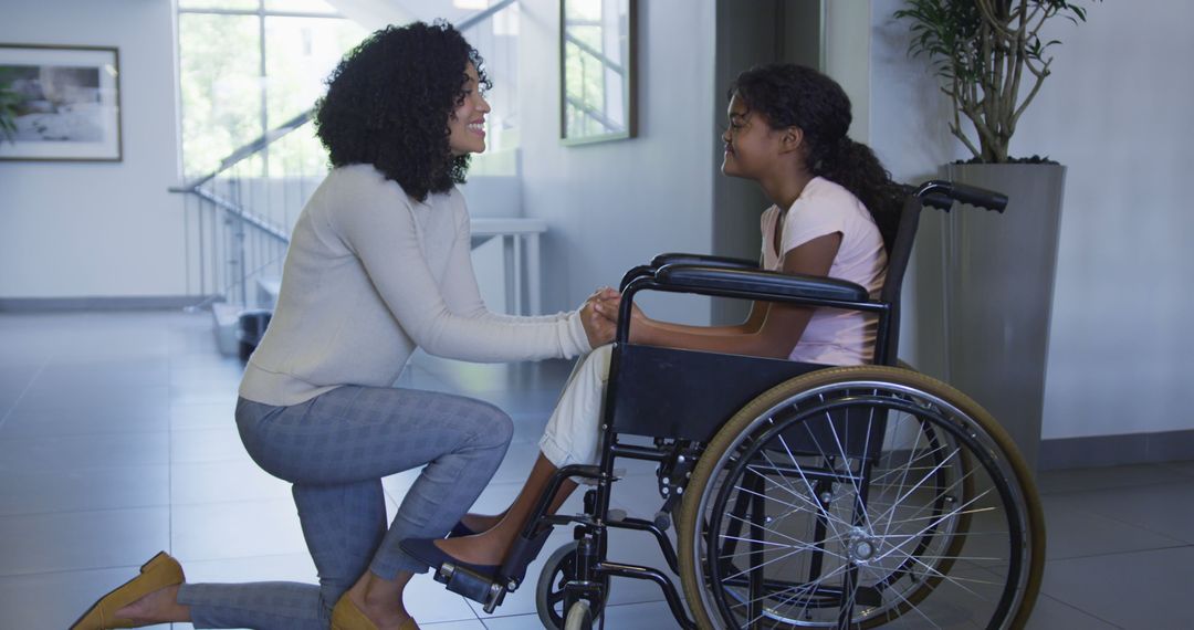 African american mother hugging her daughter sitting on a wheelchair at hospital - Free Images, Stock Photos and Pictures on Pikwizard.com