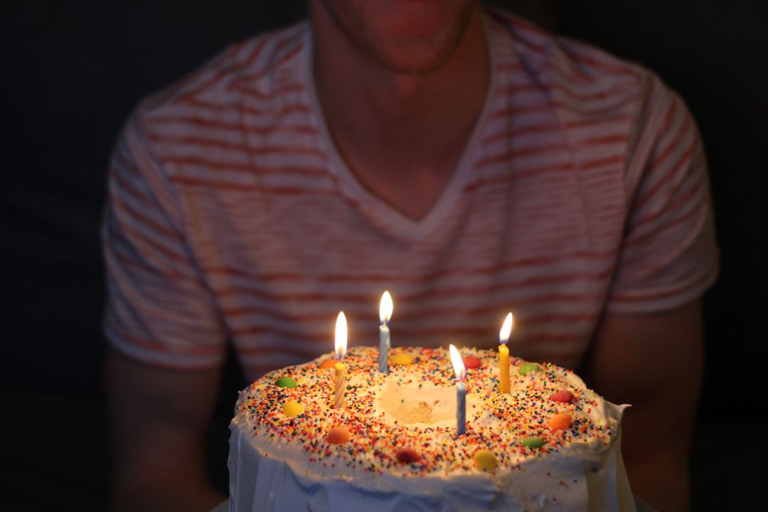 a man sitting in front of a cake with lit candles - Free Images, Stock Photos and Pictures on Pikwizard.com