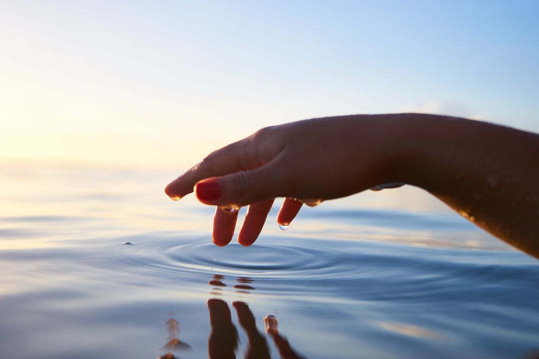a person's hand reaching out to touch the water - Free Images, Stock Photos and Pictures on Pikwizard.com