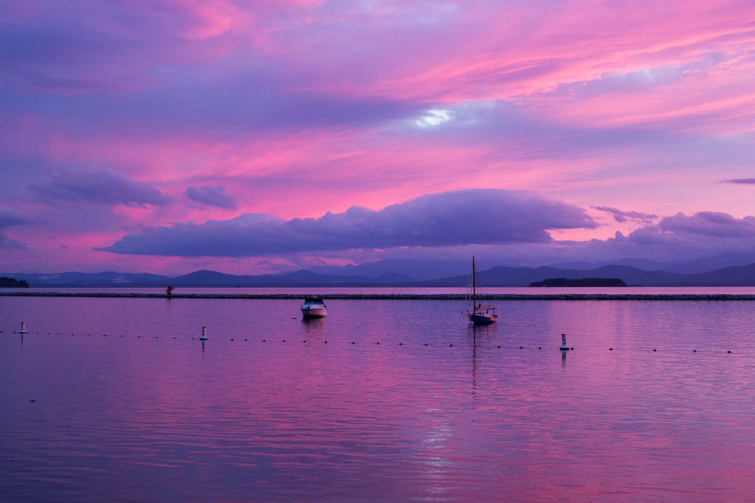 Purple sunset with boats in the water with clouds