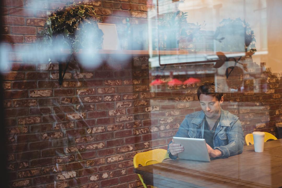 Image of a man using an iPad in a cafe - Don't skip proofreading your content - Image