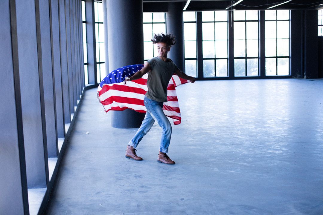African american transgender man holding american flag in empty parking garage - Free Images, Stock Photos and Pictures on Pikwizard.com