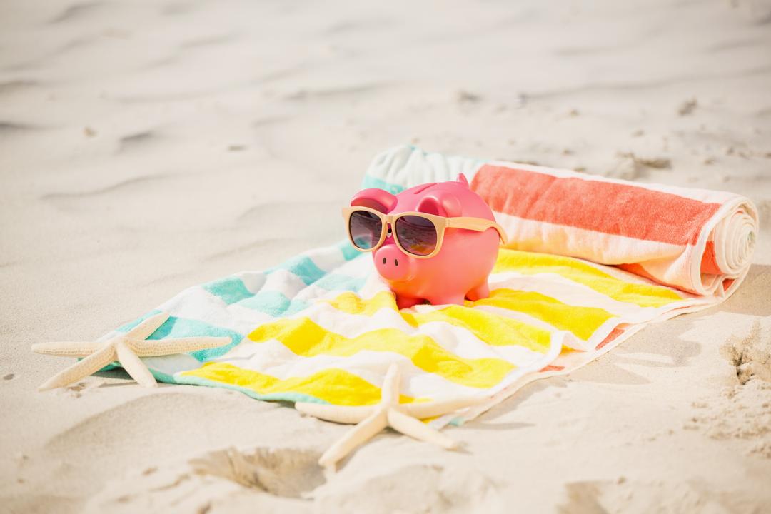 Image of a piggy bank with sunglasses at the beach - A practical guide on how to get the most out of your writing if you're planning on starting a money blog - Image