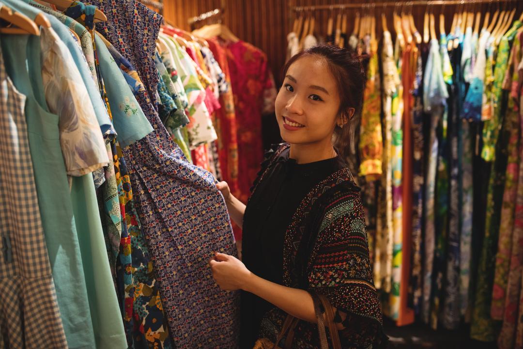 Photo of a woman smiling while picking out clothes from a rack - Tips on how to choose tone words for a fashion blog - Image