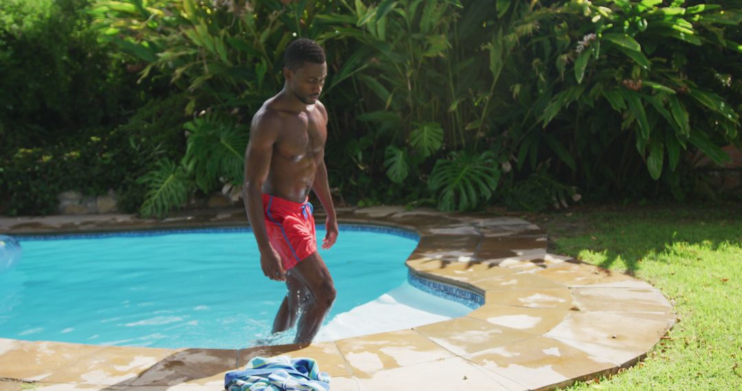 Handsome african american man walking out of in swimming pool in sunny  garden from Pikwizard